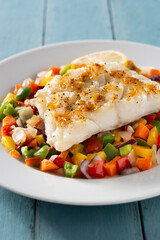 Grilled cod with vegetables on blue wooden table.Close up