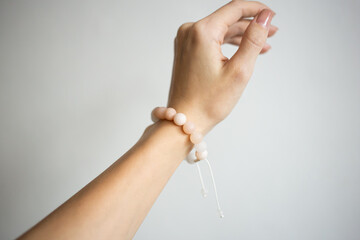 Bracelet with natural stones of different colors on a beautiful hand of a young girl on a white background