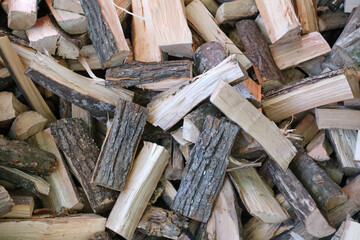 Small brown chopped firewood with grey bark pile lies