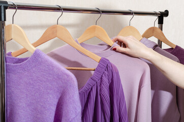 Stylist is choosing fashionable tops in trendy colors on clothes rack. Personal shopping,...