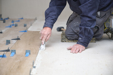Unrecognizable senior mason laying ceramic wood effect tiles.
