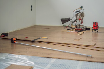 Installing new wooden laminate flooring on a warm film floor. Infrared floor heating system under laminate floor