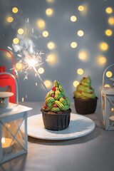 Christmas cupcake with burning sparkler on green cream tree with cowberry decor