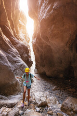 Happy alone woman wearing helmet for safety is engaged in active canyoning and hiking along the Saklikent Gorge in Turkey. New experience and outdoor leisure recreation