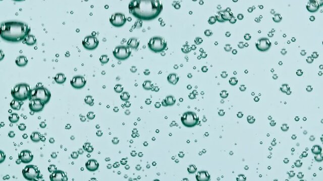Macro shot of air bubbles in water rising up on light blue background. Slow motion. High quality FullHD footage