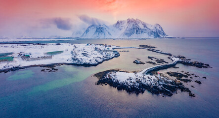 Colorful winter view from flying drone of small fishing village - Hovsund, Norway, Europe. Fantastic sunrise on Lofoten Islands. Misty morning seascape of Norwegian sea.  Life over polar circle.