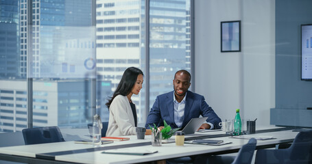 In Diverse Modern Office: Business Meeting of Businessman and Businesswoman. Businesspeople Working on International e-Commerce Project. Negotiating, Planning, Solving Problems.