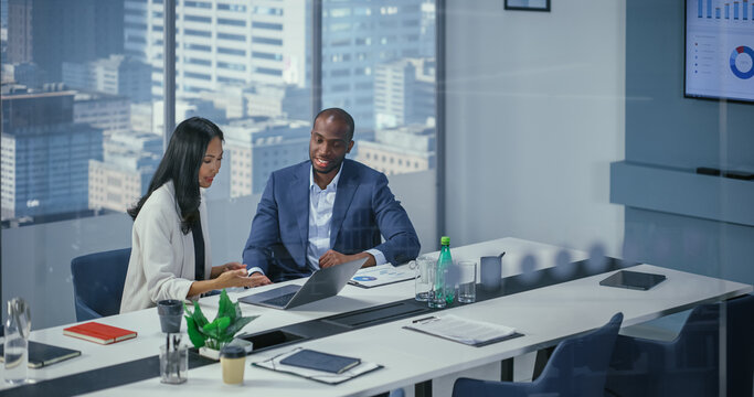In Diverse Modern Office: Business Meeting of CEO Woman and Male Executive Director Talk. Successful Smiling Businesspeople Working on e-Commerce Project. Negotiating, Planning, Signing Contract