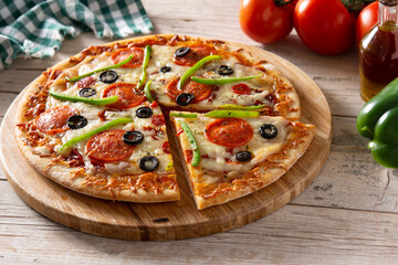 Traditional supreme pizza on wooden table