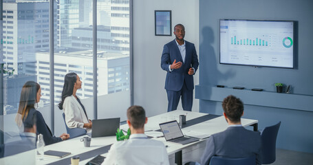 Diverse Office Conference Room Meeting: Charismatic Black Digital Entrepreneur Presents e-Commerce Fintech Product to a Group of Investors. Wall TV with Big Data Analysis, Infographics, Statistics