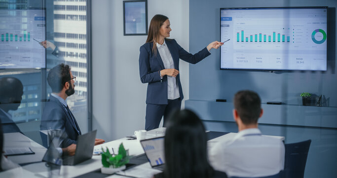 Diverse Office Conference Room Meeting: Motivated Female Digital Startup Owner Presents e-Commerce Fintech Growth Statistics to a Group of Investors. Wall TV with Big Data Analysis, Infographics
