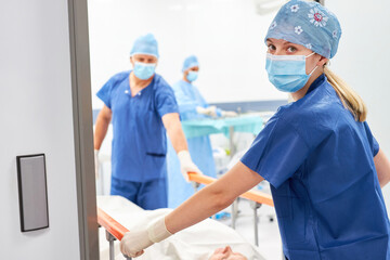 Krankenschwester und Pfleger schieben Patient im Krankenbett