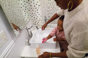 Mother and daughter washing hands in bathroom