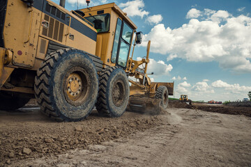 The grader performs excavation work on the construction of the road.
