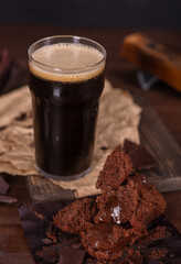 Glass of beer stout standing on wooden board with chocolate muffin