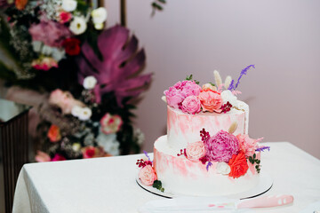 Pastel pink layer wedding cake decorated with white peony flowers