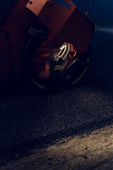 Rolling asphalt at night with headlights. Road construction.