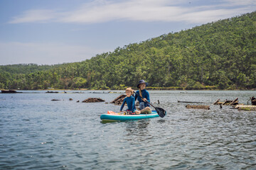 happy family of two, mother and son, enjoying stand up paddling during summer vacation