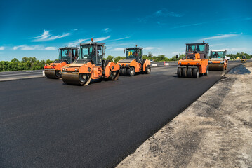 Fototapeta na wymiar Rollers rolling fresh hot asphalt on the new road. Road construction.
