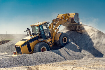 A large powerful loader overloads a pile of rubble in a concrete plant.