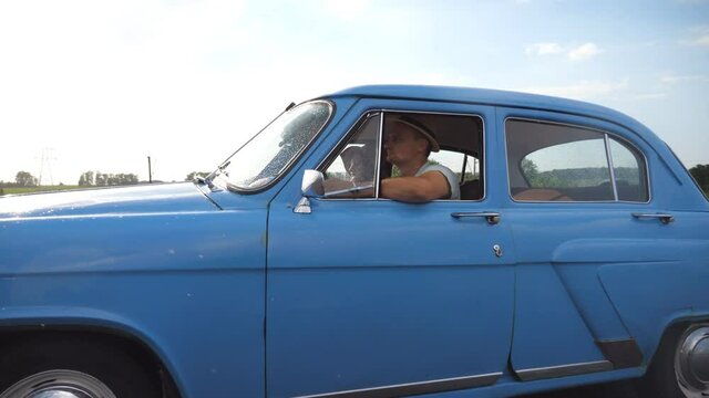 Classic old car traveling on highway on rainy summer day. Young couple driving on country road in vintage automobile. Trip at the retro auto. Concept of summer vacation or holiday. Slow motion Closeup
