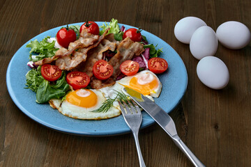 Fried eggs with bacon, lettuce and cherry tomatoes