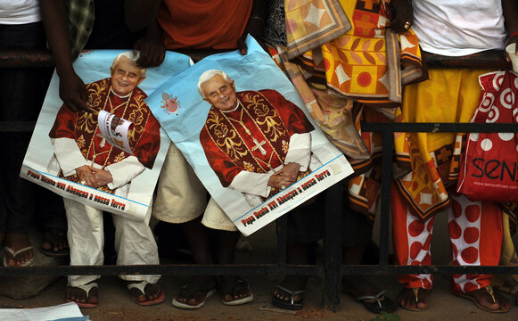 Faithful hold pictures of Pope Benedict XVI as they wait for him to pass in the street of Luanda during the second leg of his trip to Africa