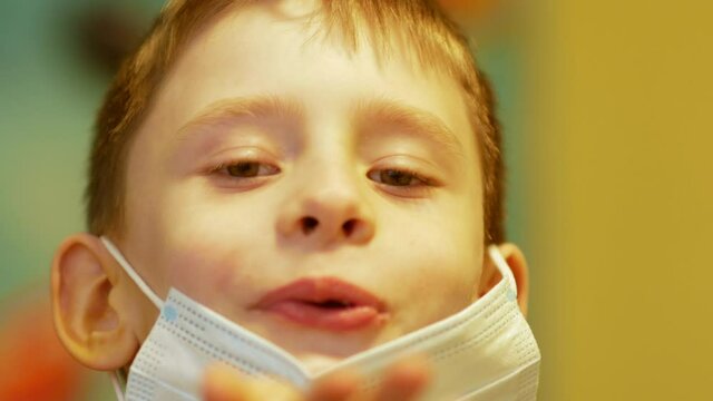 Portrait of a Caucasian boy, 7-8 years old, taking off his medical card and blowing a kiss on Valentine's Day. Greetings from his son on Mother's Day. selective focus