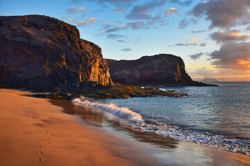 The west coast of Lanzarote at a beautiful sunset. A sandy beach and a blue sky with some clouds. Canary Islands, Spain.
