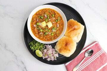  Indian Mumbai Street style Pav Bhaji, garnished with peas, raw onions, coriander, and Butter. Spicy thick curry made of out mixed vegetables served with pav over white background with copy space.