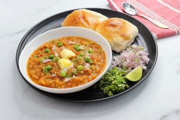  Indian Mumbai Street style Pav Bhaji, garnished with peas, raw onions, coriander, and Butter. Spicy thick curry made of out mixed vegetables served with pav over white background with copy space.
