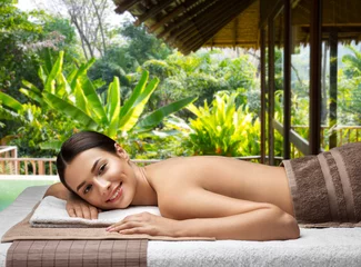 Wall murals Massage parlor wellness, beauty and relaxation concept - young woman lying at spa or massage parlor over bungalow at exotic resort in thailand on background