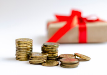 Iron gold coins on the background of a gift tied with a red satin ribbon. The concept of finance, investment, savings and cash.