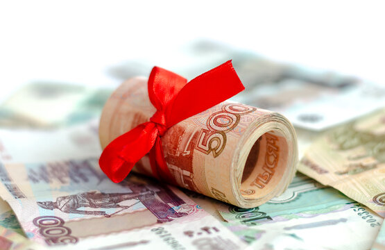 A bundle of Russian money tied with a red satin ribbon with a face value of 5000 rubles, lying on Russian banknotes. The concept of finance, investment, savings and cash.