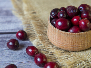 large cranberries in a wooden bowl on a wooden background. Healthy food and nutrition. Place for text.