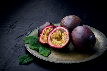 Fresh ripe passion fruits (maracuyas) on dark background with water drops