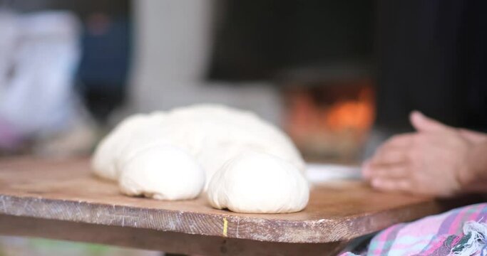 Baker hands kneading dough in flour on the table
