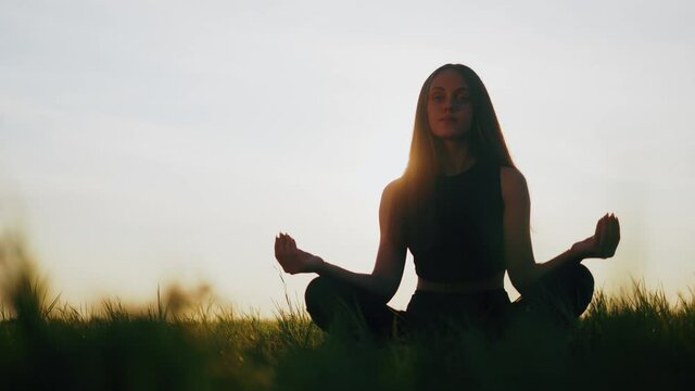 Silhouette of young woman practicing yoga on the nature at sunset. active meditation a relax concept. woman meditation in nature in the park. sport recreation concept sunset