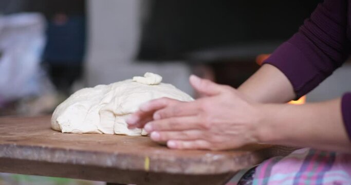 Baker hands kneading dough in flour on the table
