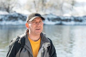 Portrait of a smiling man in a cap on the river in winter