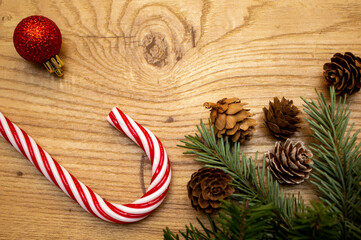 Christmas tree branches, cones and red and white candy stick on the wooden background. Holiday concept. Flat lay