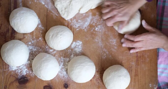 Baker hands kneading dough in flour on the table
