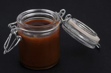 Bocal de caramel au beurre salé en gros plan sur fond noir