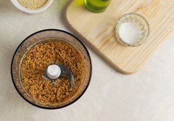 Sesame seeds are blended in a blender bowl in your home kitchen. The process of making a traditional tahini sauce. Levantine cuisine concept. Top view.