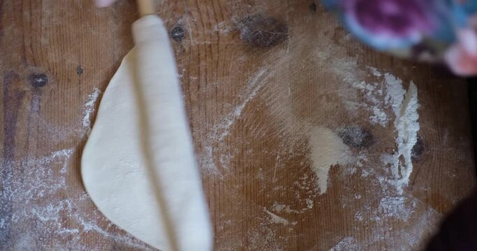 Female Hands Of Baker Rolls Dough In Flour On Wooden Board On Table With A Rolling Pin, In Bakery Shop, Woman Making Pizza Using Traditional Recipe At Home.