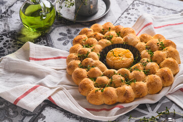 Roasted camembert cheese and homemade bread heart shaped and thyme on rustic background. French cheese. Concept of romantic love for Valentines Day. Top view, copy space.