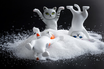Three funny toy kittens are having fun in a heap of white powder. The concept of rest and...