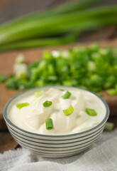 sour cream with sliced onion on wooden surface