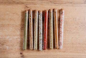 Different spices in glass tubes on a wooden background.