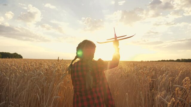 Child's flight dream. Happy child playing with toy plane in field against blue sky. baby child runs across field at sunset with toy airplane in his hand. Happy flight dream.